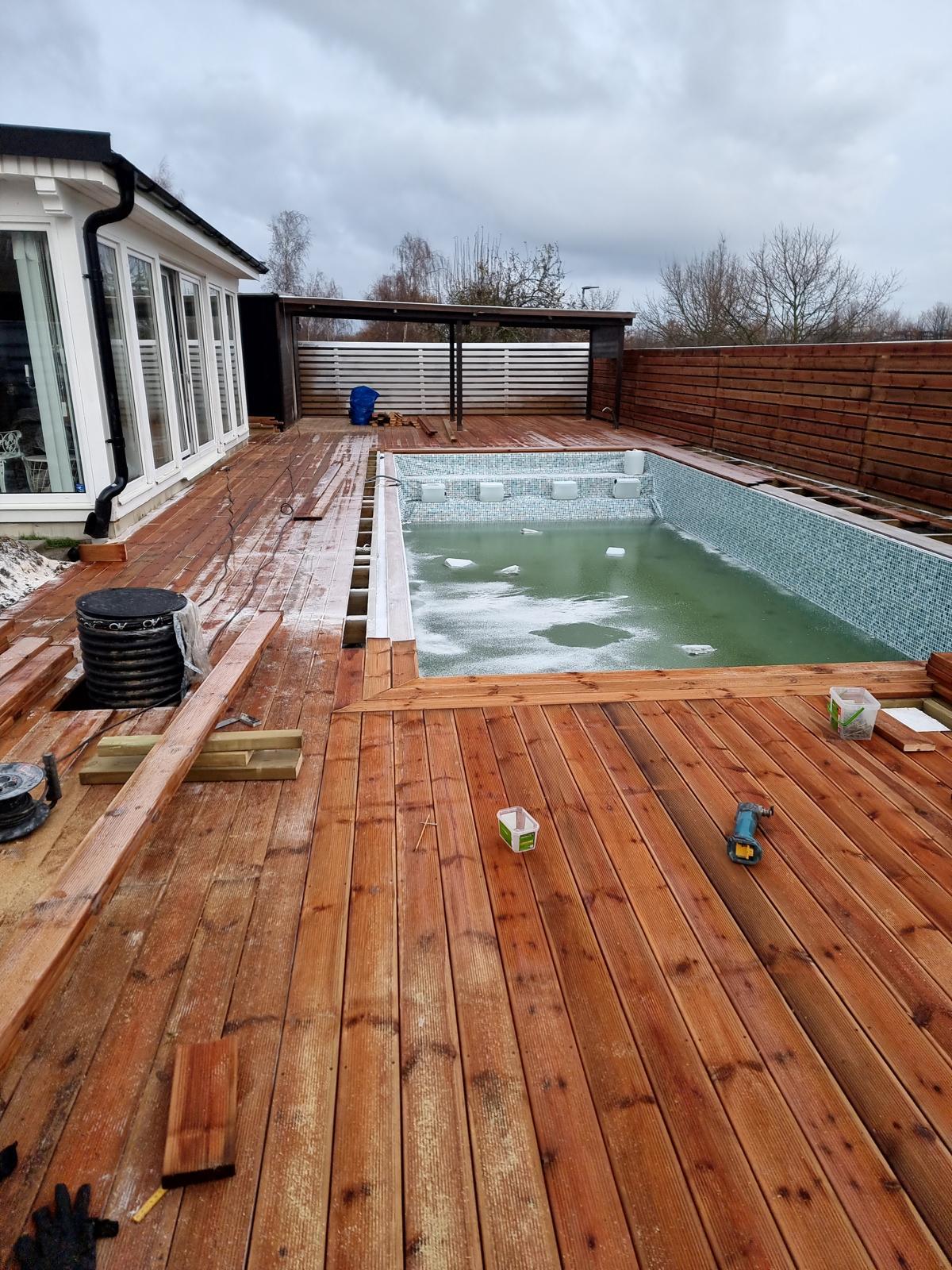 Poolområde med trädäck och insynsskydd